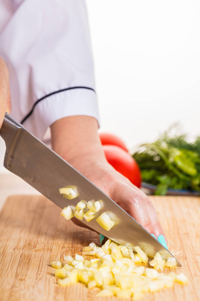 Cook cuts pepper with a knife on wooden board - Foto, immagini