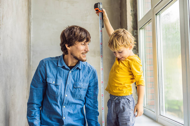 Little boy playing with tool while repairing window with dad together while renovation in house. - 写真・画像