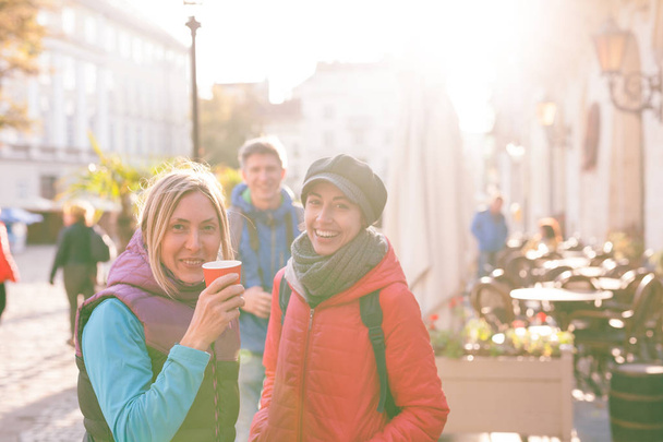 Vriendinnen drinken koffie. Twee vrienden lopen in de stad. Vrouwen reizen naar Europese steden. Meisjes communiceren op een stad straat. - Foto, afbeelding
