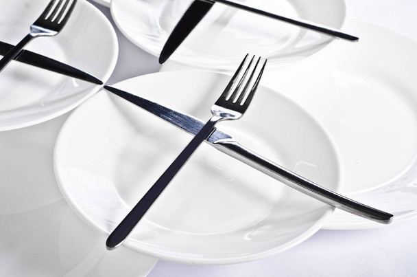 Abstraction from forks and knives. Beautiful table setting with restaurant utensils in various combinations in an interesting, creative design on a white and light background and in the form. - Photo, image