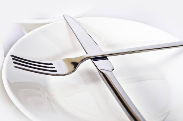 Abstraction from forks and knives. Beautiful table setting with restaurant utensils in various combinations in an interesting, creative design on a white and light background and in the form. - Zdjęcie, obraz