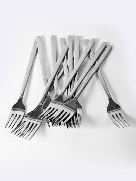 Abstraction from forks. Beautiful table setting with restaurant utensils in various combinations in an interesting, creative design on a white and light background and in the form. - Foto, Imagen
