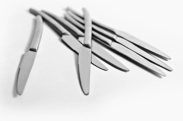 Abstraction from knives. Beautiful table setting with restaurant utensils in various combinations in an interesting, creative design on a white and light background and in the form. - Fotó, kép