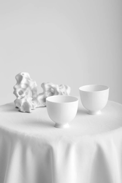Close-upweergave van tabel met witte cups geïsoleerd op witte achtergrond - Foto, afbeelding