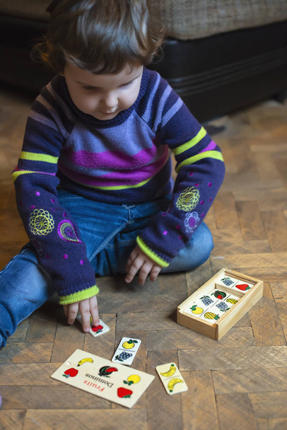 Дитина грає з фруктами, пофарбованими в дерев'яні блоки. Маленька дівчинка грає на підлозі вдома. Фрукти концептуальна метафора
. - Фото, зображення