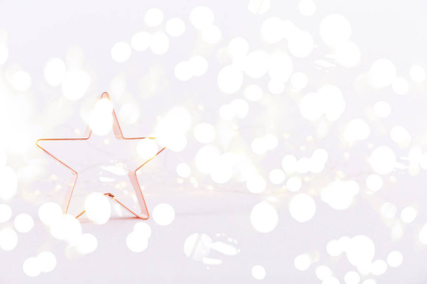 Звезда медь резак печенья на белом блестящем фоне с боке огни. Рождественский и новогодний фон. Горизонтальные, яркие огни боке фон
 - Фото, изображение