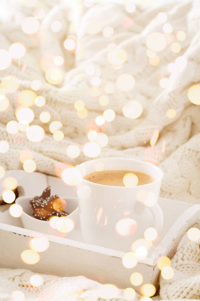 Caneca de bebida quente com biscoitos de chocolate em um cobertor de lã branca. Bebida quente, casa aconchegante e conceito de estação fria. Vertical, luzes brilhantes bokeh fundo
 - Foto, Imagem