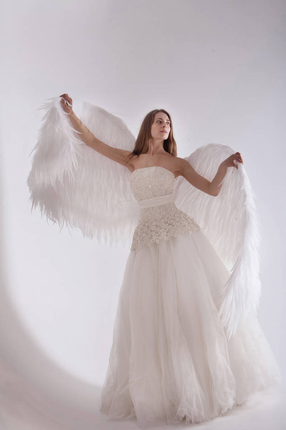 Girl in white dress with angel wings on white background. Angel-woman - Zdjęcie, obraz