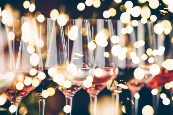 Víno brýle za sebou. Formou tabulky oslava ochutnávka vína. Noční život, oslava a zábava koncept. Horizontální, chladné tónovaný obrázek, jasná světla bokeh pozadí - Fotografie, Obrázek