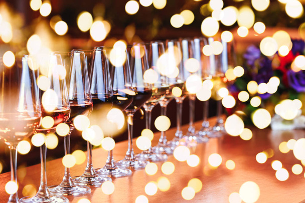 Kieliszki z rzędu do wina. Bufet celebracja tabeli z degustacją wina. Koncepcja celebracja, rozrywki i nocnego życia. Poziome, jasne światła bokeh tło - Zdjęcie, obraz