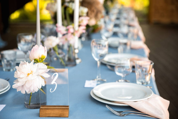 Feestelijke tafel, versierd met bloemen en kaarsen op een zilveren kandelaar op blauwe tafellaken - Foto, afbeelding