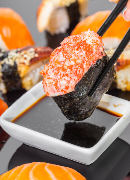 sticks keep sushi gunkan with salmon and caviar in soy sauce - Zdjęcie, obraz