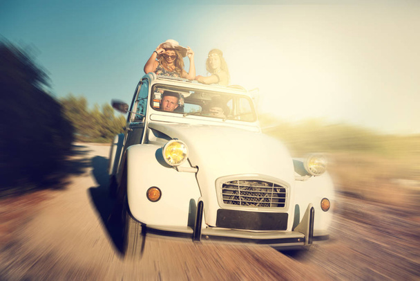 Grupo de amigos felizes em um carro ao pôr do sol no verão
. - Foto, Imagem