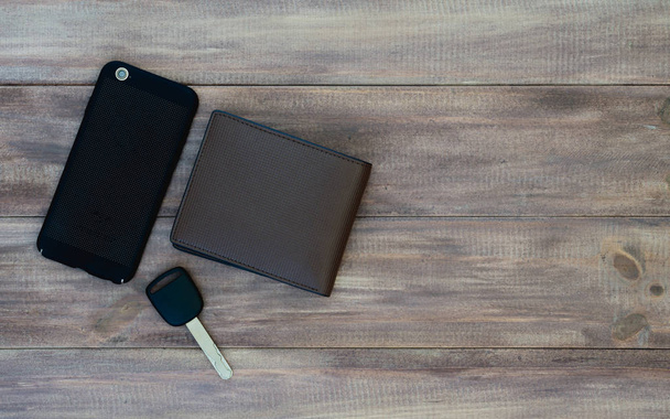 Top view of man set. Wallet, car key and smartphone on wooden background. Top view with copy space. - Foto, imagen