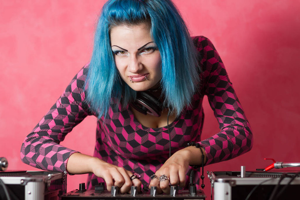 Cute young girl with blue dyed hari and pink outfit playing music records on a professional equipment - Foto, afbeelding