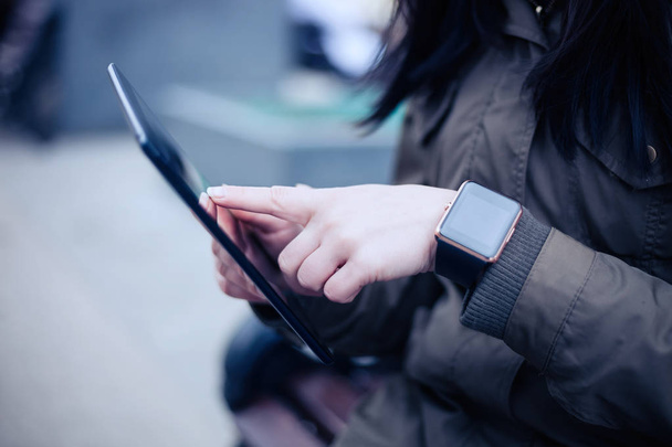 Woman using tablet pc while wearing smart watch on her wrist. This new devices lets you always stay connected to internet and social media networks from anywhere you want. - Foto, imagen