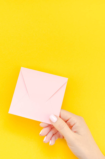 Nainen käsi pastellimanikyyri tilalla pieni rakkaus tuhatvuotinen vaaleanpunainen kirje kopio tilaa lihavoitu keltainen tausta luova minimaalinen tyyli. Konsepti malli Valentine loma naisellinen blogi
 - Valokuva, kuva