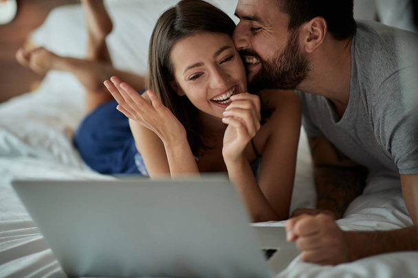 Happy in bed - Funny young couple with laptop in the bed - Foto, immagini