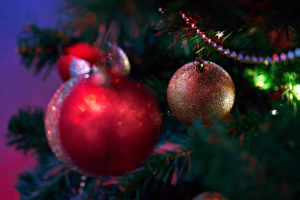 Рождественская елка украшена безделушками и другими традиционными орнаментами в красивом красном свете с копировальным пространством
 - Фото, изображение