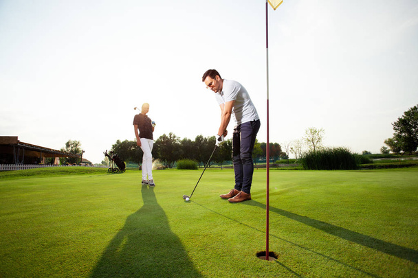 Young sportive couple playing golf on a golf course - Image - Fotó, kép