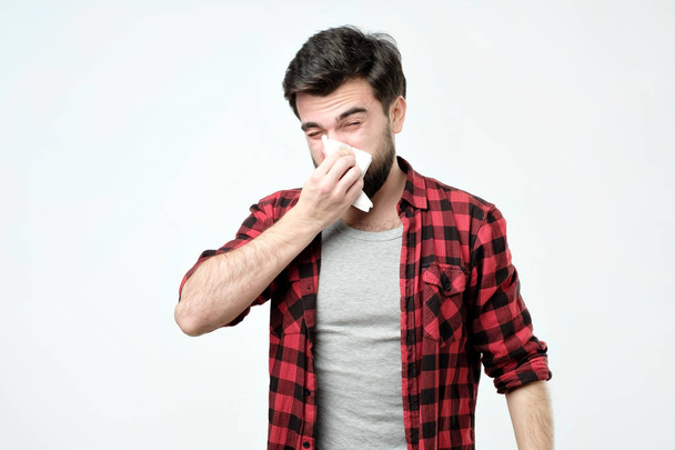 Bearded man has running nose, rubs nose with handkerchief, being ill, caught cold - Foto, afbeelding