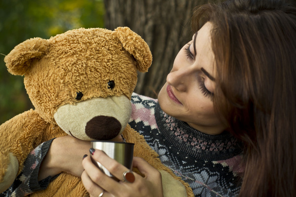 Girl posing in the forest in autumn with a teddy bear - Foto, afbeelding