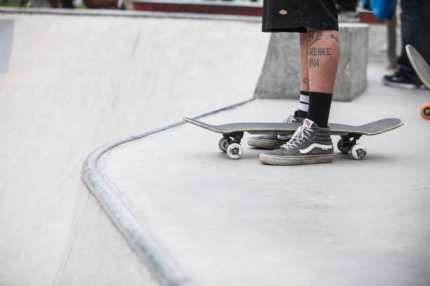 MOSCOW - 15 MAY, 2016: Summer street skateboarding contest in outdoor skate park.Extreme skating in concrete skatepark outside.Skateboarder exercising.Active dynamic extremal sport.Young skater boy with tattoos  - Foto, Imagen