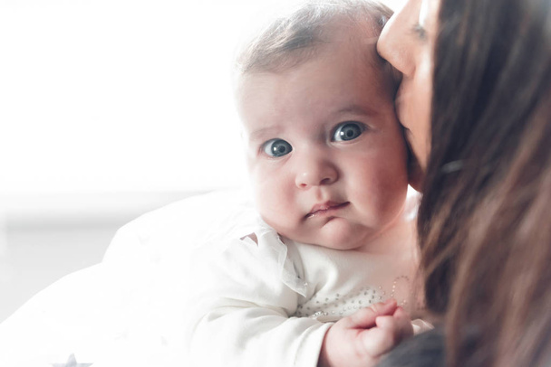 giovane madre che tiene la sua piccola neonata in grazioso vestito bianco
 - Foto, immagini