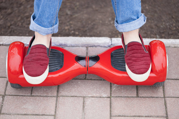 girl in shoes riding on modern red electric mini segway  - Photo, Image