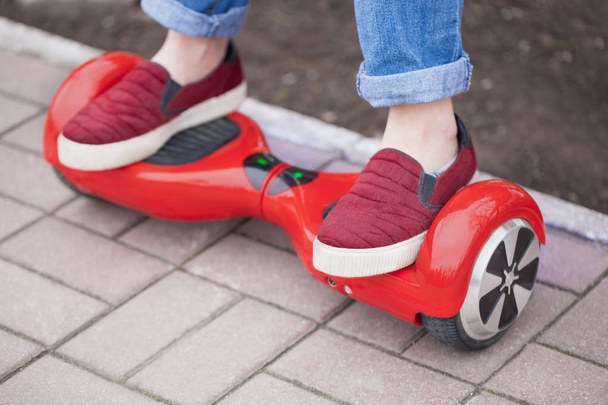 girl in shoes riding on modern red electric mini segway  - Фото, изображение