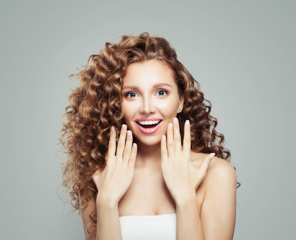 Surprised woman. Beautiful student girl with long curly hair. Presenting your product. Positive emotion. Expressive facial expressions - Photo, Image