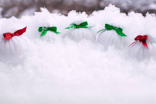 Torby z kolorowe łuki z darami stoją w śniegu na tle drzew - Zdjęcie, obraz