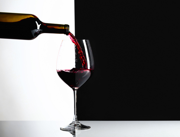 Rotwein wird in ein Glas gegossen. reflexiven Hintergrund, kopieren Sie Platz für Ihren Text. - Foto, Bild