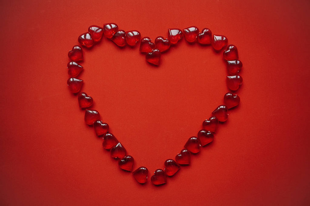 Un gran corazón de muchos corazones pequeños sobre un fondo rojo
. - Foto, Imagen
