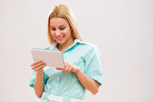 Portret van jonge verpleegster die therapieën op digitale tablet onderzoekt. - Foto, afbeelding