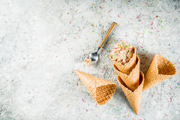 Їстівне сире печиво Тісто, солодкий сучасний десерт, з конусами вафельного морозива на сірому кам'яному фоні, місце для тексту
 - Фото, зображення