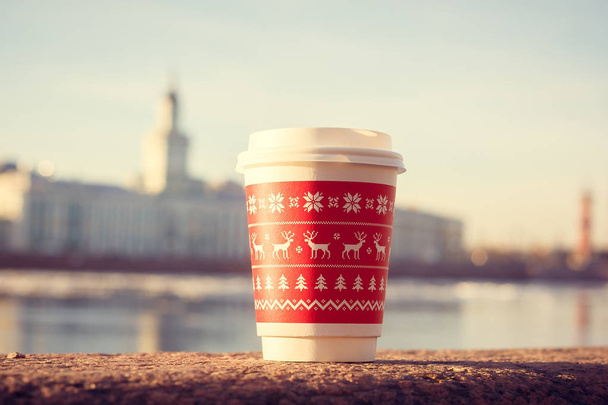 červený umělohmotný pohár s kávou-go na kamenném parapetu na břehu řeky - Fotografie, Obrázek