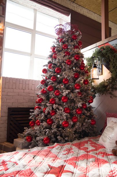 Árvore de Natal com bolas vermelhas e flocos de neve brancos, cama e travesseiros. Ano Novo
 - Foto, Imagem