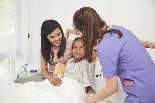 Femmina medico e giovane asiatico piccolo paziente con e madre sorridente mentre medico venire a visitare
 - Foto, immagini