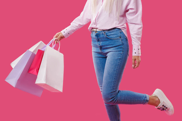 Female hands holding a shopping bags over pink background - Foto, Imagem