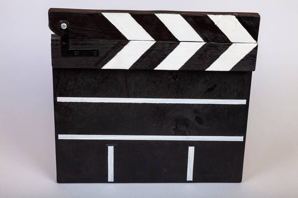 Klapky pro označení začátku film nebo videoklip z dřeva a malované černé a bílé s pruhy v uzavřené formě na bílém pozadí izolované detail - Fotografie, Obrázek