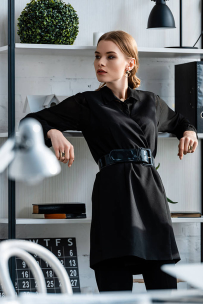 stylish woman in black formal wear at workplace looking away - Foto, afbeelding