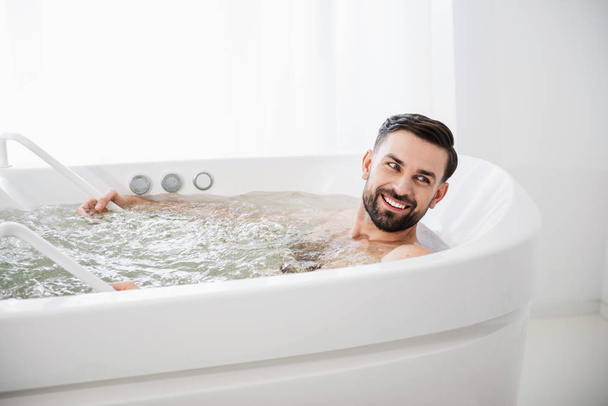 Emotionaalinen mies hymyilee ollessaan hydro hieronta kylpyamme
 - Valokuva, kuva