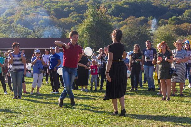 Dakhovskaya, Russia - September 22,  2018: young guy and girl dancing in the meadow at the Adygei cheese festival in the foothills of the Caucasus - Foto, afbeelding