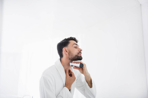 Close up of careful man standing and shaving his beard - Zdjęcie, obraz