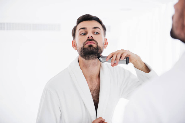 Serious man putting head up while shaving his neck - Valokuva, kuva