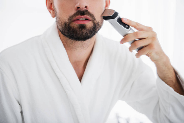Close up of the man shaving his face with shaving machine - Foto, imagen