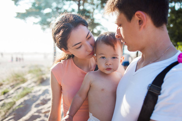 Portrait of happy young family with charming baby. Picnic on the beach - 写真・画像