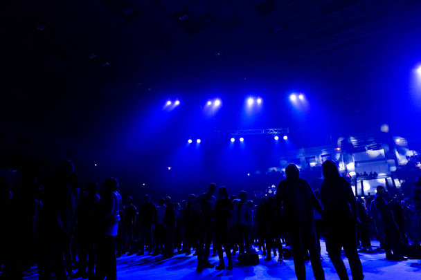La folla dei concerti sotto i riflettori blu. Silhouette di spettatori ad un concerto rock in una grande sala
. - Foto, immagini