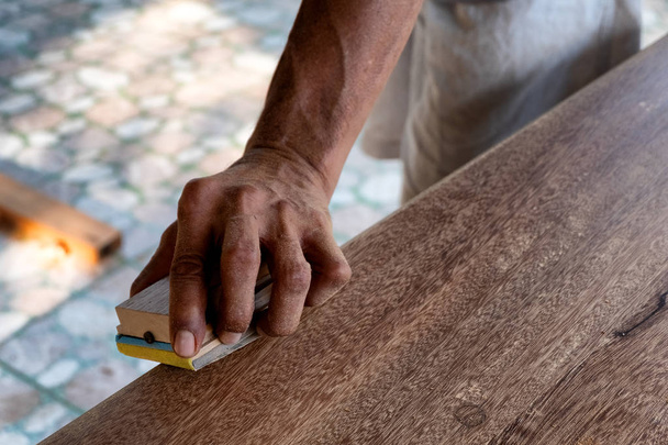 Карпентер работает в своей мастерской. Плотник делает дверь из большого дерева
. - Фото, изображение